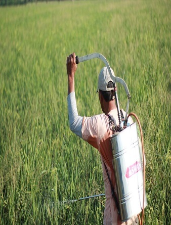 A man spraying a field with pesticides.